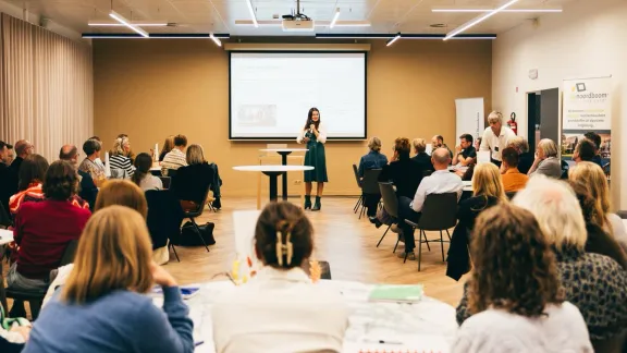 mensen aan ronde tafels in zaal