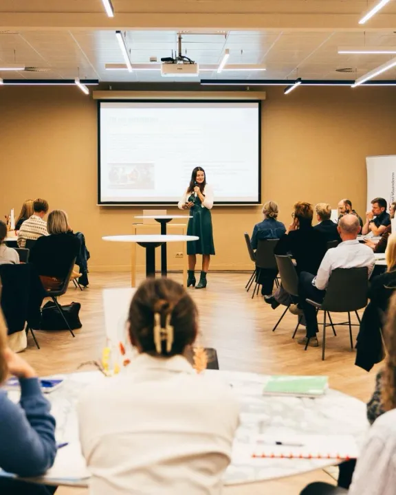 mensen aan ronde tafels in zaal